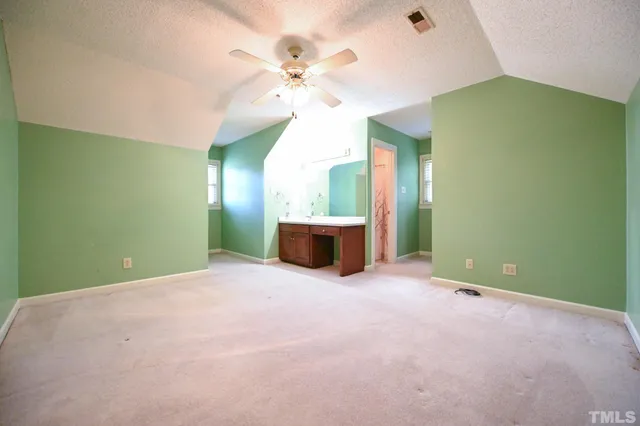 a view of an empty room with a chandelier fan and a fireplace