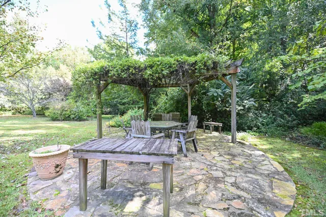 a view of a patio with table and chairs potted plants and large tree