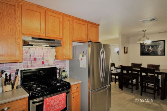 1100 West Iowa Avenue Ridgecrest, CA 93555 - Photo 7 of 19 a kitchen with stainless steel appliances a stove a refrigerator and wooden cabinets