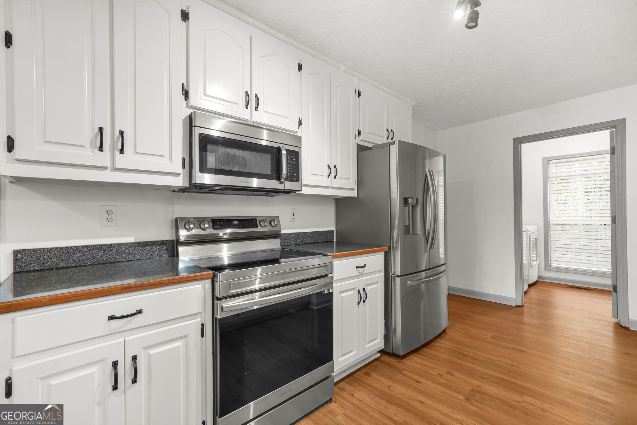 156 Pine Street Covington, GA 30014 - Photo 18 of 37 a kitchen with stainless steel appliances white cabinets and wooden floors