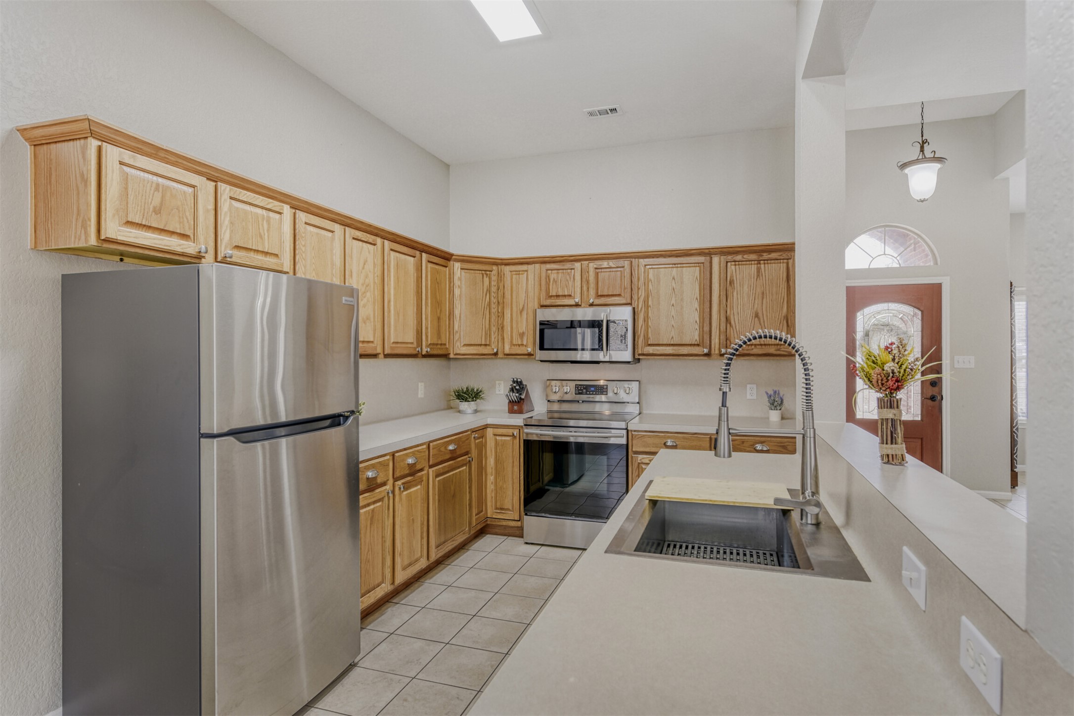 104 Spring Branch Bastrop, TX 78602 - Photo 20 of 32 Kitchen with stainless steel appliances, light countertops, light tile patterned floors, pendant lighting, and light brown cabinets