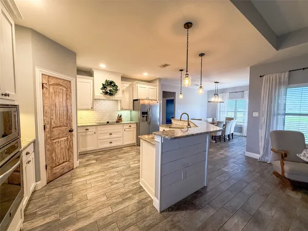 a kitchen with stainless steel appliances kitchen island granite countertop a refrigerator and a stove top oven