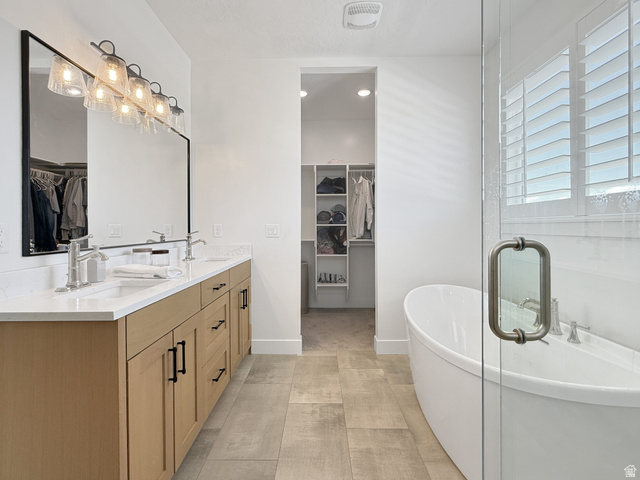 916 Rocky Mountain Way Elk Ridge, UT 84651 - Photo 24 of 54 Full bath with a spacious closet, double vanity, a freestanding bath, and recessed lighting