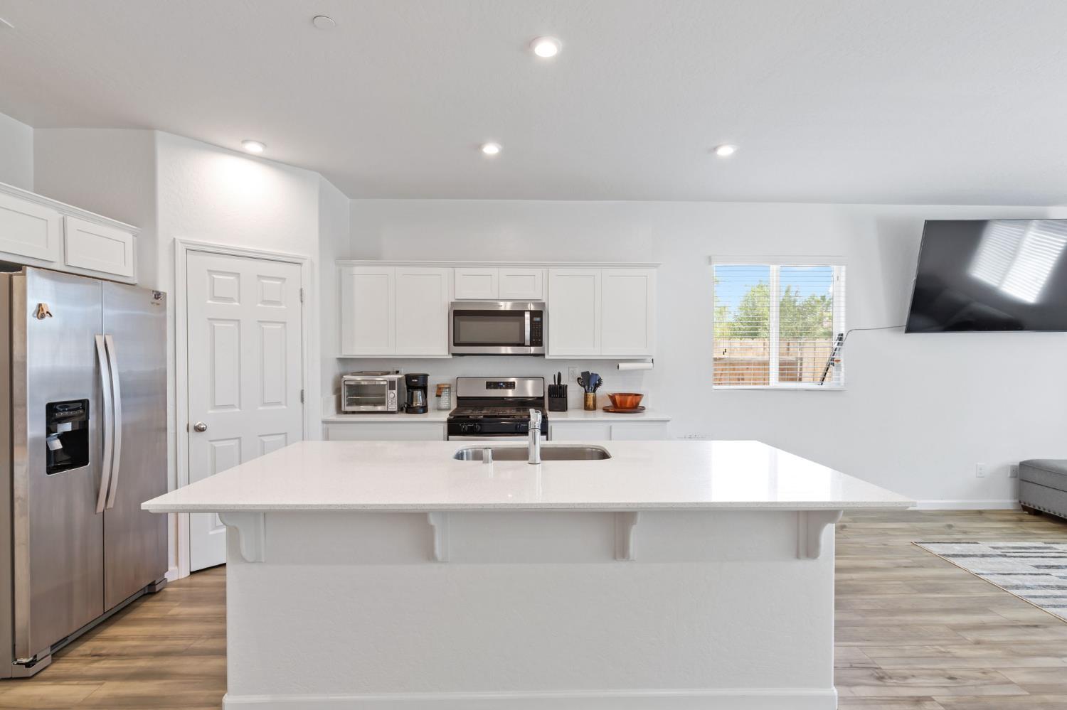 282 Rosebriar Street Madera, CA 93638 - Photo 2 of 28 a kitchen with stainless steel appliances a microwave a sink a stove a microwave a sink a refrigerator and white cabinets