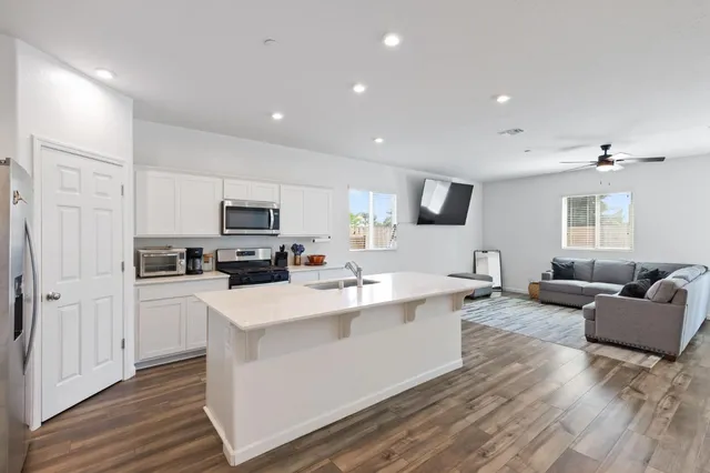 a living room with stainless steel appliances kitchen island granite countertop a couch and a view of kitchen