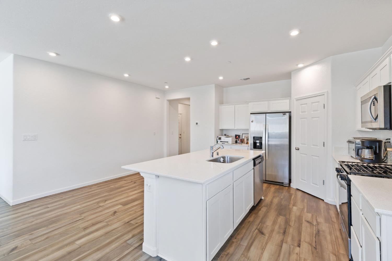 282 Rosebriar Street Madera, CA 93638 - Photo 5 of 28 a large white kitchen with wooden floor and sink