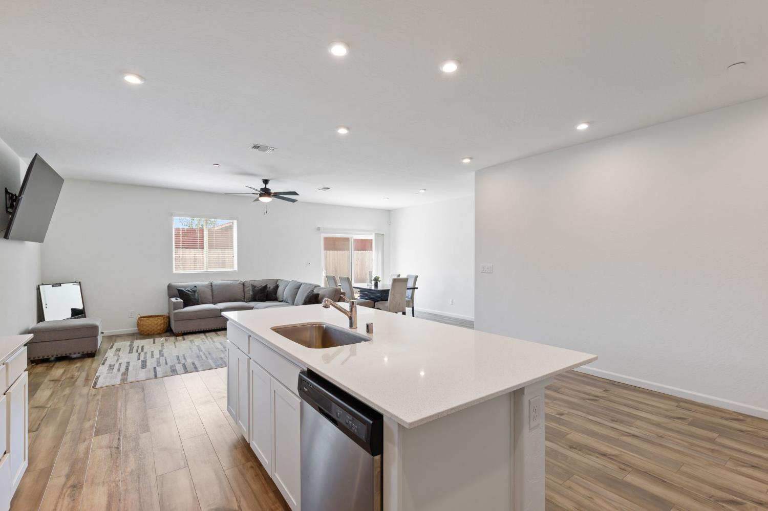 282 Rosebriar Street Madera, CA 93638 - Photo 7 of 28 a kitchen with a sink dishwasher and white cabinets with wooden floor