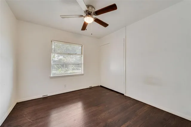 an empty room with wooden floor ceiling fan and windows