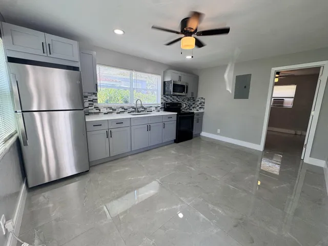 a kitchen with stainless steel appliances granite countertop a refrigerator a sink a stove a microwave and island