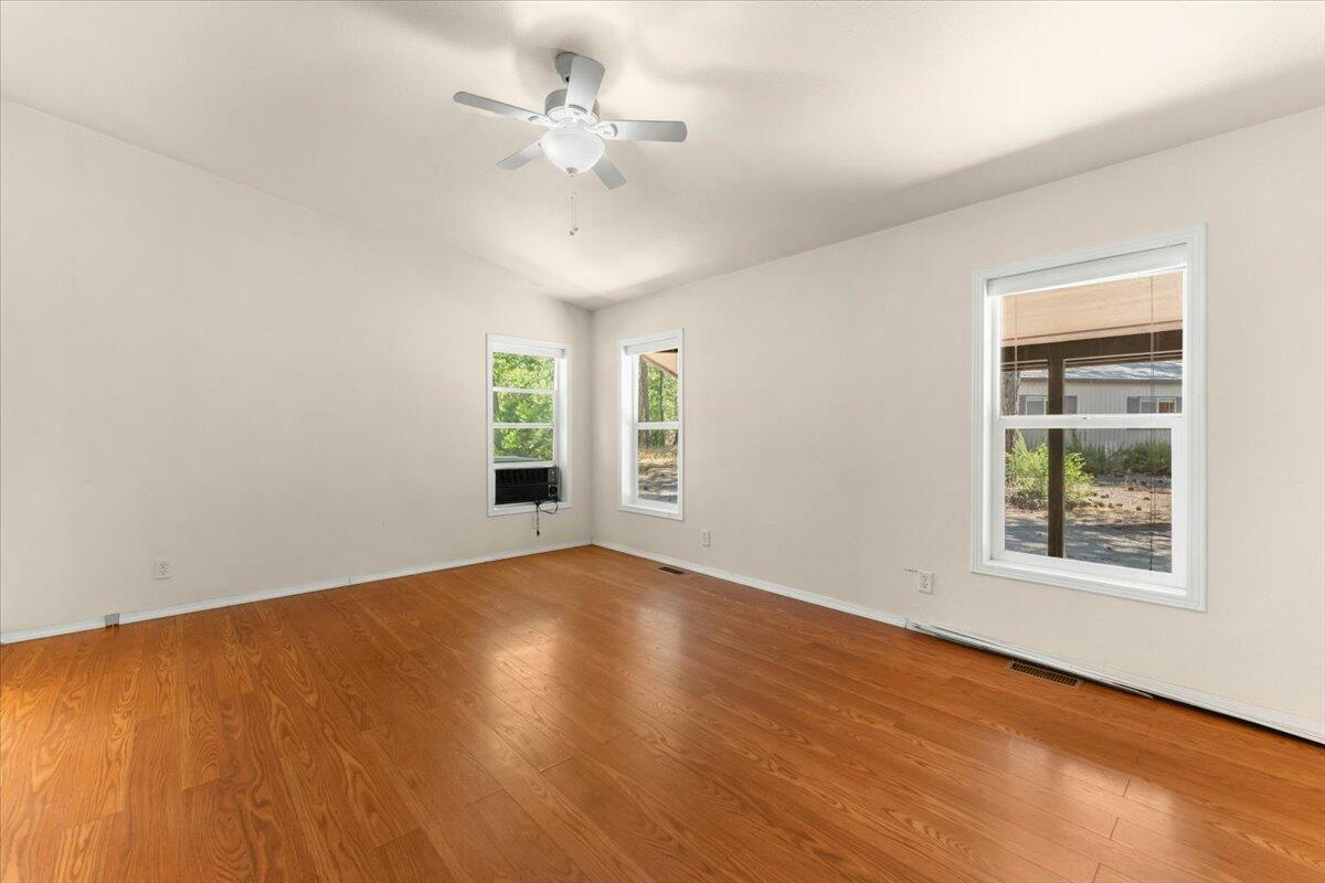 15288 Sherwood Forrest Road Oak Run, CA 96069 - Photo 19 of 91 an empty room with wooden floor chandelier fan and windows