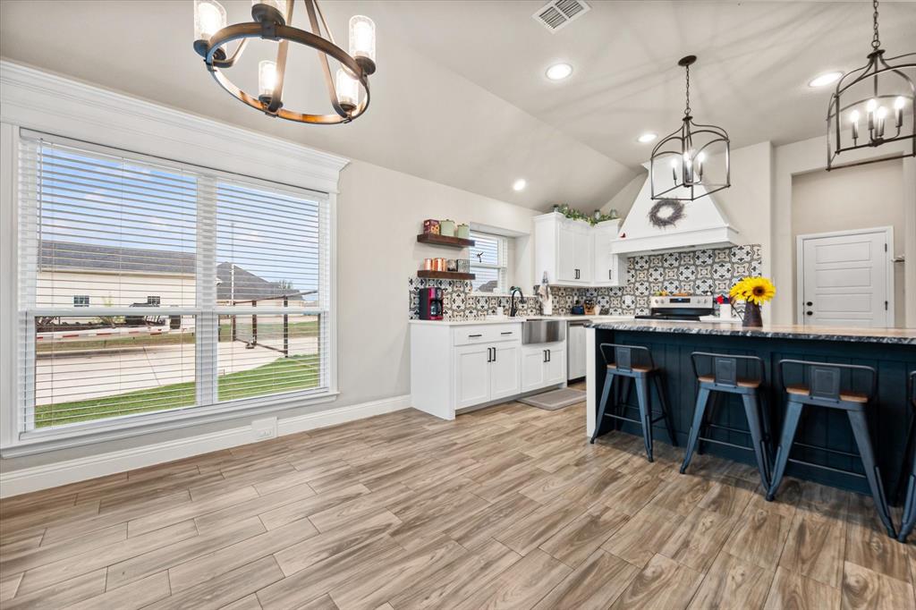 6365 Rhoden Avenue Godley, TX 76044 - Photo 12 of 31 a kitchen with stainless steel appliances granite countertop a stove top oven a dining table and chairs with wooden floor