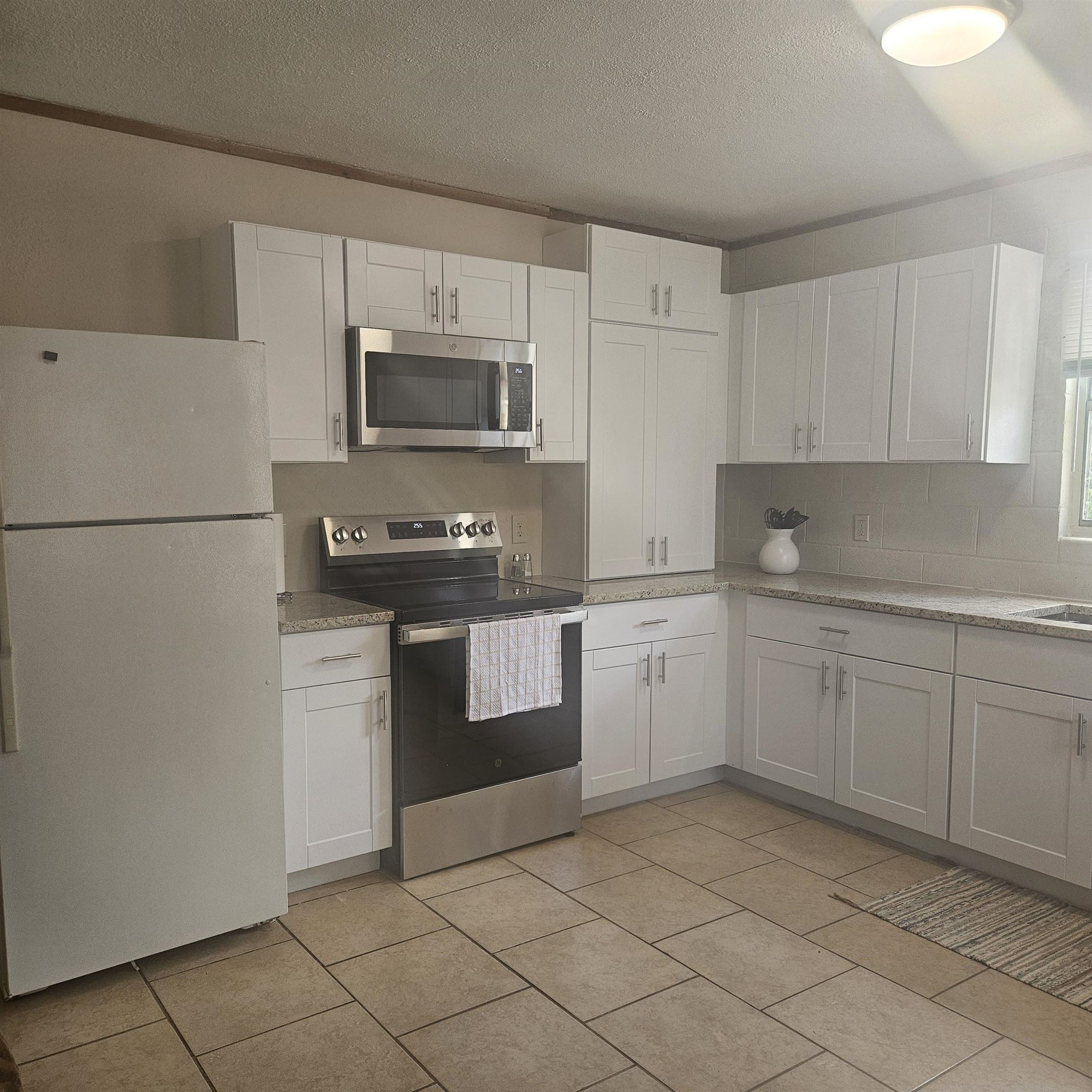 12001 Ranch Road 2341 Burnet, TX 78611 - Photo 6 of 18 A well-equipped kitchen features crisp white cabinetry, stainless appliances and granite counters, i