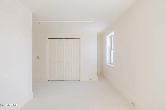a view of an empty room with wooden floor and window