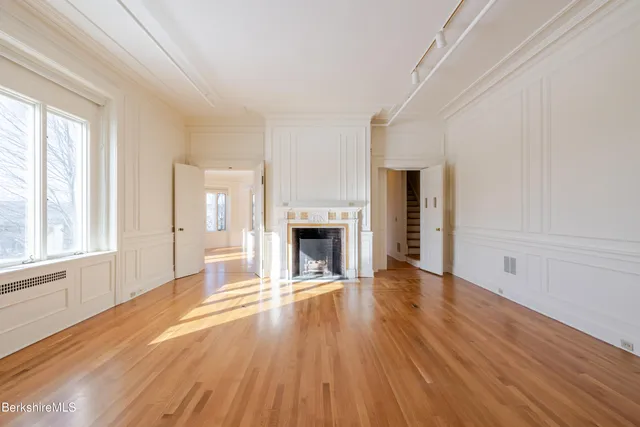 a view of a livingroom with wooden floor and a fireplace