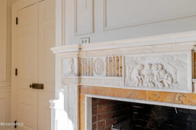 a view of an empty room with wooden floor fireplace and a window