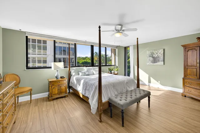 a spacious bedroom with a bed a table chair and wooden floor