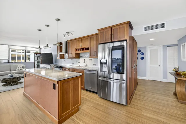 a kitchen with stainless steel appliances kitchen island granite countertop a refrigerator stove and sink