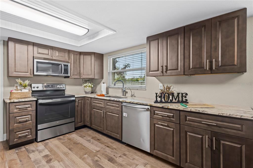 1437 Glenview Road Palm Harbor, FL 34683 - Photo 33 of 69 a kitchen with granite countertop cabinets stainless steel appliances a sink and a window