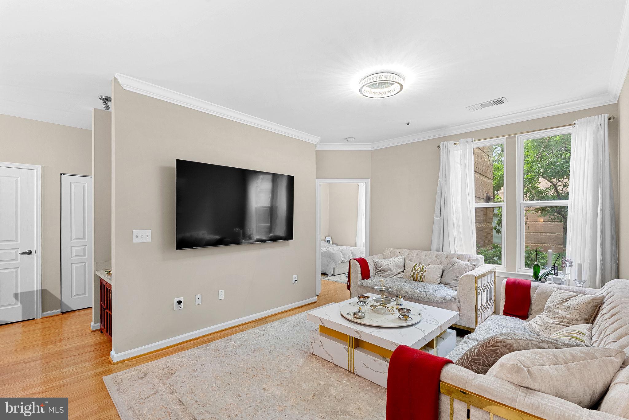 12001 Market Street, Unit 106 Reston, VA 20190 - Photo 12 of 45 a living room with furniture and a flat screen tv
