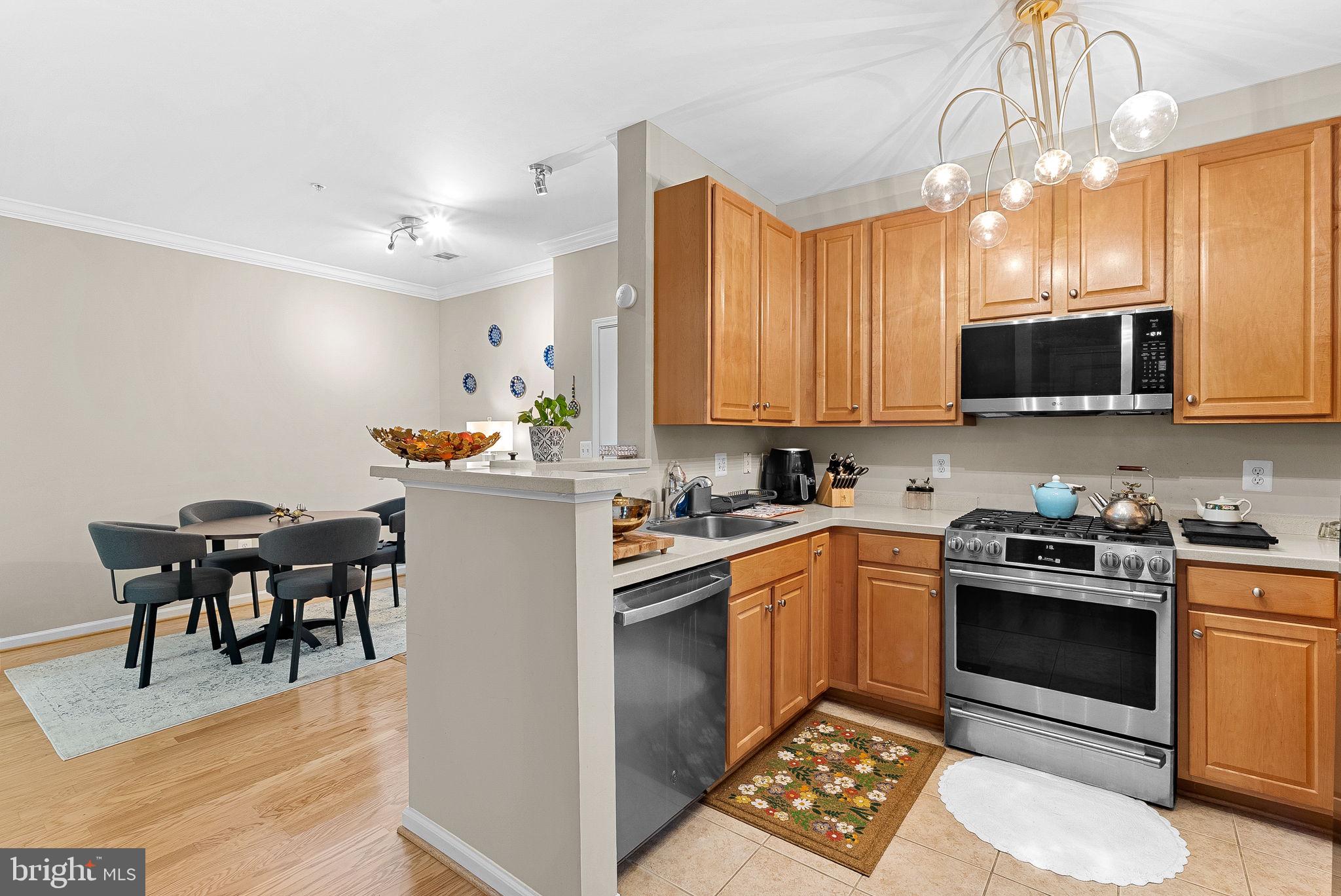 12001 Market Street, Unit 106 Reston, VA 20190 - Photo 15 of 45 a kitchen with stainless steel appliances granite countertop a stove top oven a sink dishwasher and white cabinets with wooden floor