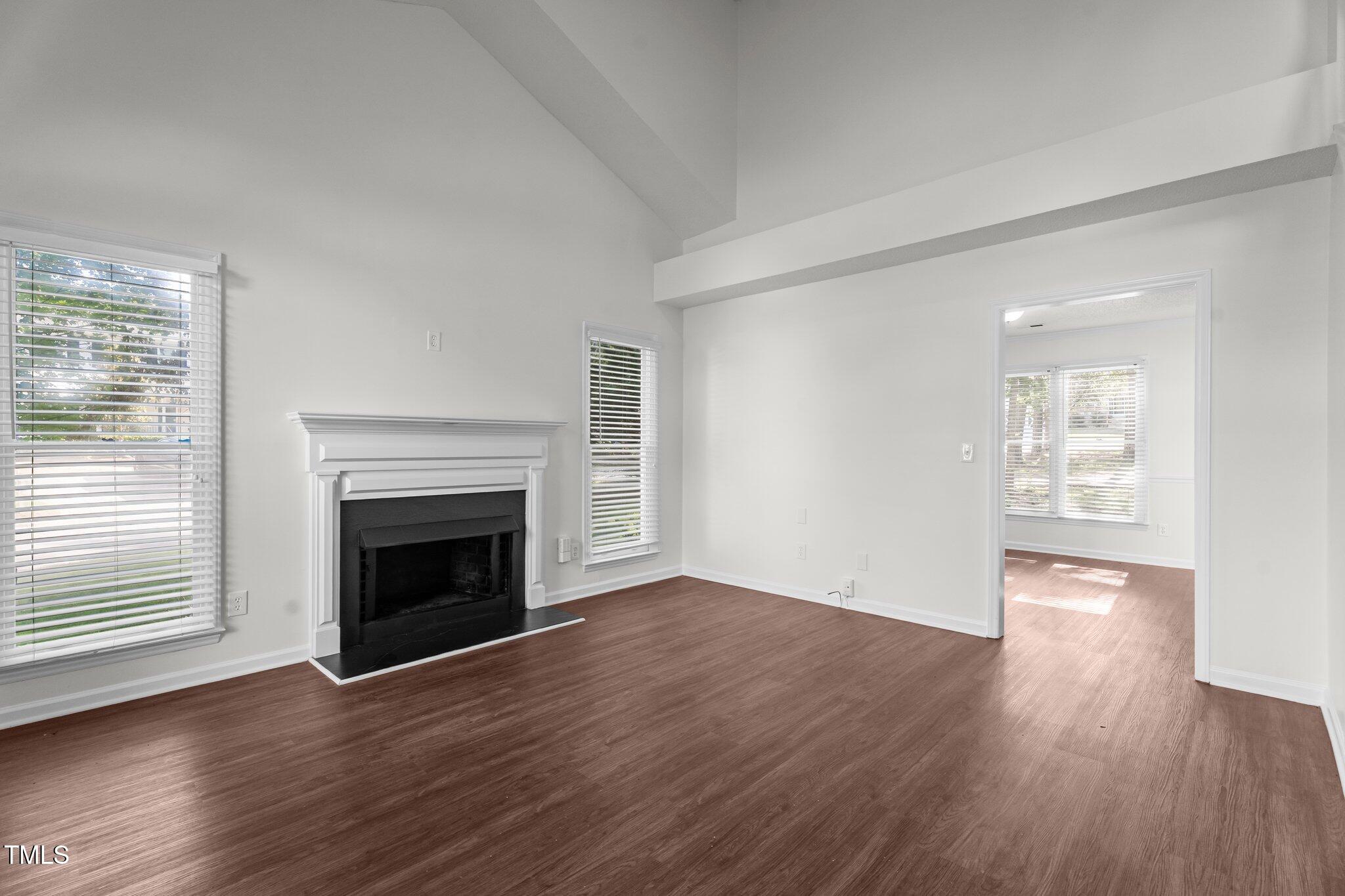 3624 Singleleaf Lane Raleigh, NC 27616 - Photo 9 of 40 an empty room with wooden floor fireplace and windows