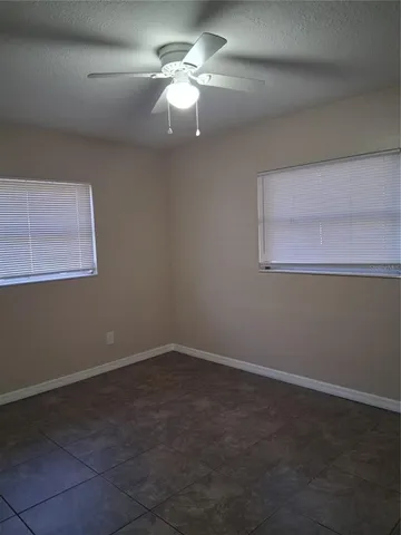 a view of a livingroom with an empty space a ceiling fan and window