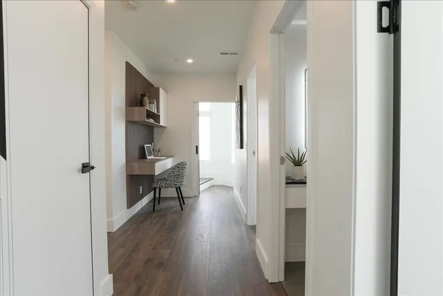 a view of a hallway with wooden floor and a living room