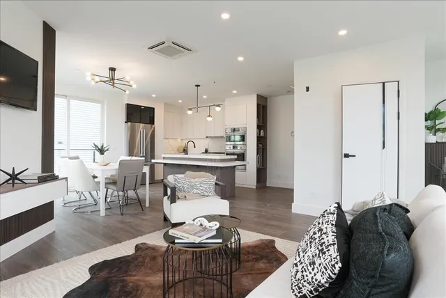 a living room with furniture kitchen view and a flat screen tv