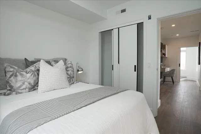 a bedroom with a large bed and wooden floor