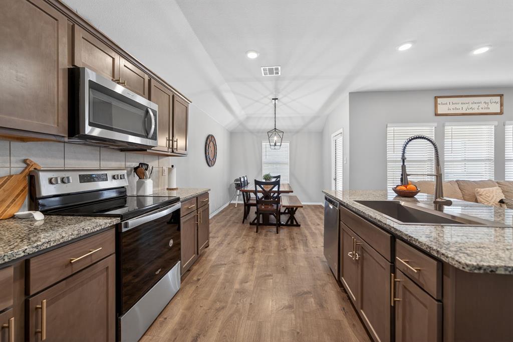 800 Rustic Way Royse City, TX 75189 - Photo 9 of 21 a kitchen with stainless steel appliances granite countertop a stove top oven a sink dishwasher a dining table and chairs with wooden floor