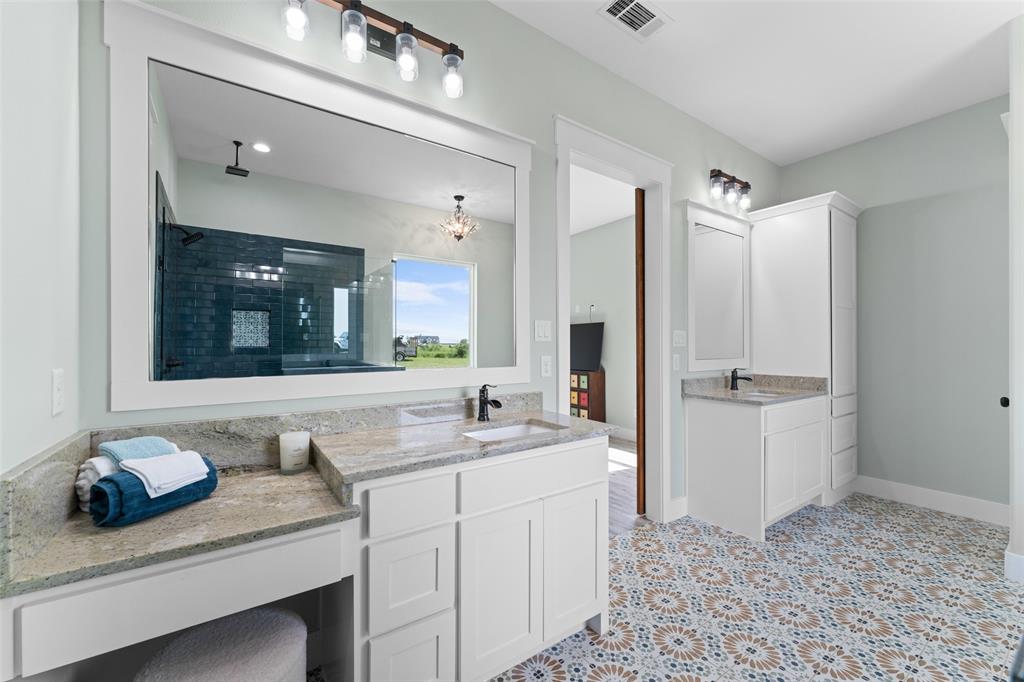 4411 Fm 751 Wills Point Wills Point, TX 75169 - Photo 23 of 40 Dual vanity bathroom featuring patterned floor tiling, white cabinetry, stone countertops, and a built-in shower with dark subway tile