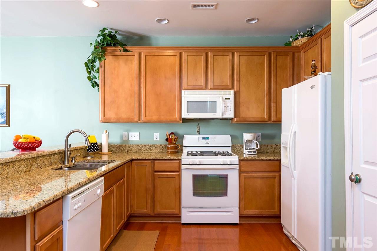 8228 Belneath Court Raleigh, NC 27613 - Photo 3 of 17 a kitchen with stainless steel appliances granite countertop a stove a sink dishwasher and a refrigerator with wooden cabinets
