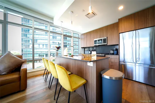 a kitchen with stainless steel appliances granite countertop a refrigerator a stove a sink dishwasher a dining table and chairs with wooden floor