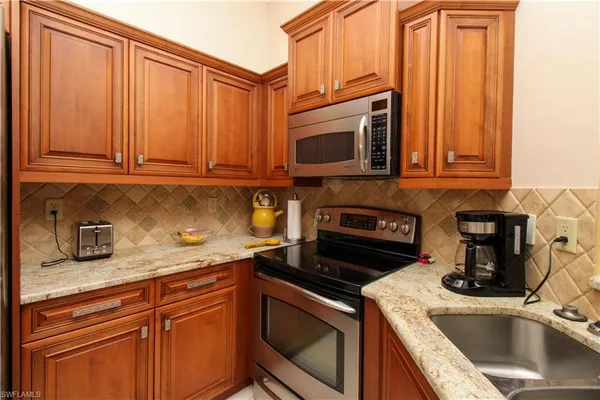 a kitchen with granite countertop a sink stove and microwave