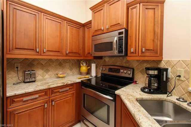 a kitchen with granite countertop a sink stove and microwave