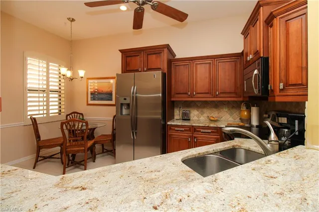 a kitchen with stainless steel appliances kitchen island granite countertop a sink refrigerator and cabinets
