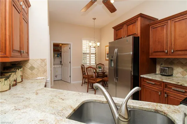 a kitchen with stainless steel appliances kitchen island granite countertop a refrigerator and a sink