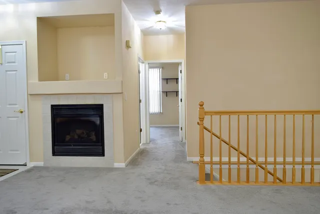 a view of a hallway to an empty room with fireplace and a window