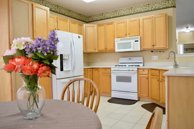 a kitchen with stainless steel appliances granite countertop a refrigerator a sink dishwasher and white cabinets with wooden floor