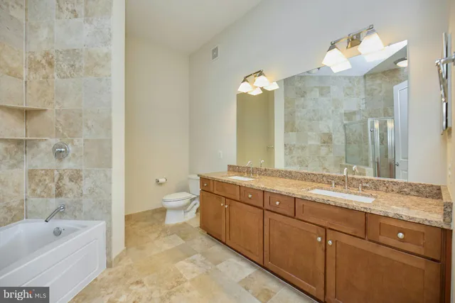 a spacious bathroom with a granite countertop sink a toilet and a bathtub