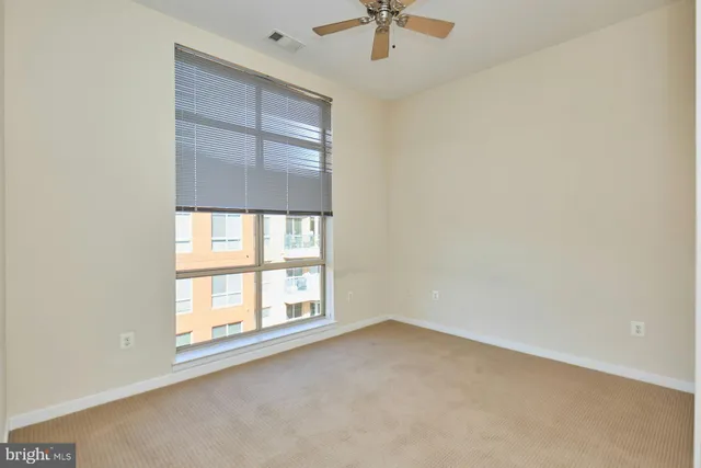 an empty room with a window and ceiling fan