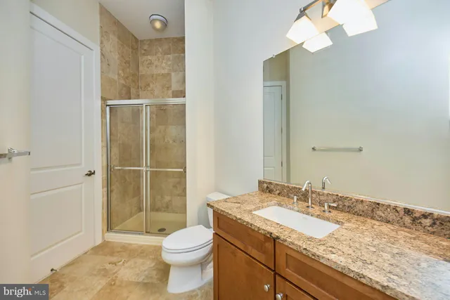 a bathroom with a granite countertop sink toilet and shower
