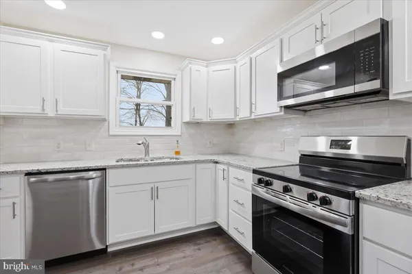 a kitchen with stainless steel appliances granite countertop a sink dishwasher a stove microwave and oven with cabinets
