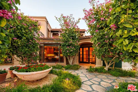 a front view of a house with a yard and potted plants