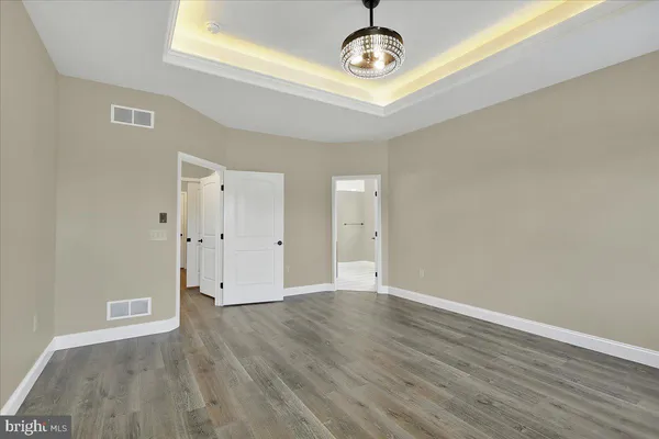 an empty room with wooden floor and a ceiling fan