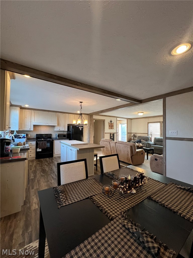 53720 Highway 681 Reedsville, OH 45772 - Photo 7 of 25 Open-concept living space featuring a dining area with a dark-finish table, a kitchen with white cabinetry and dark countertops, wood-finish flooring, recessed lighting, and exposed ceiling beams