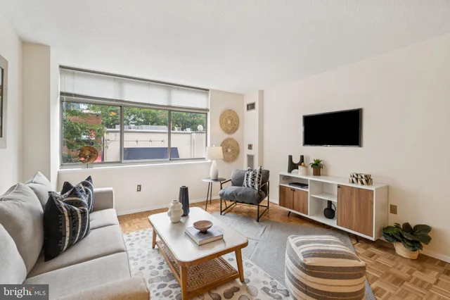 a living room with furniture a flat screen tv and a floor to ceiling window