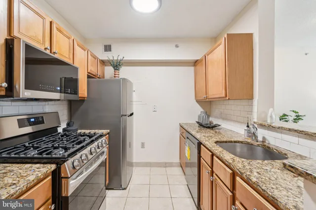 a kitchen with granite countertop a sink stove and refrigerator