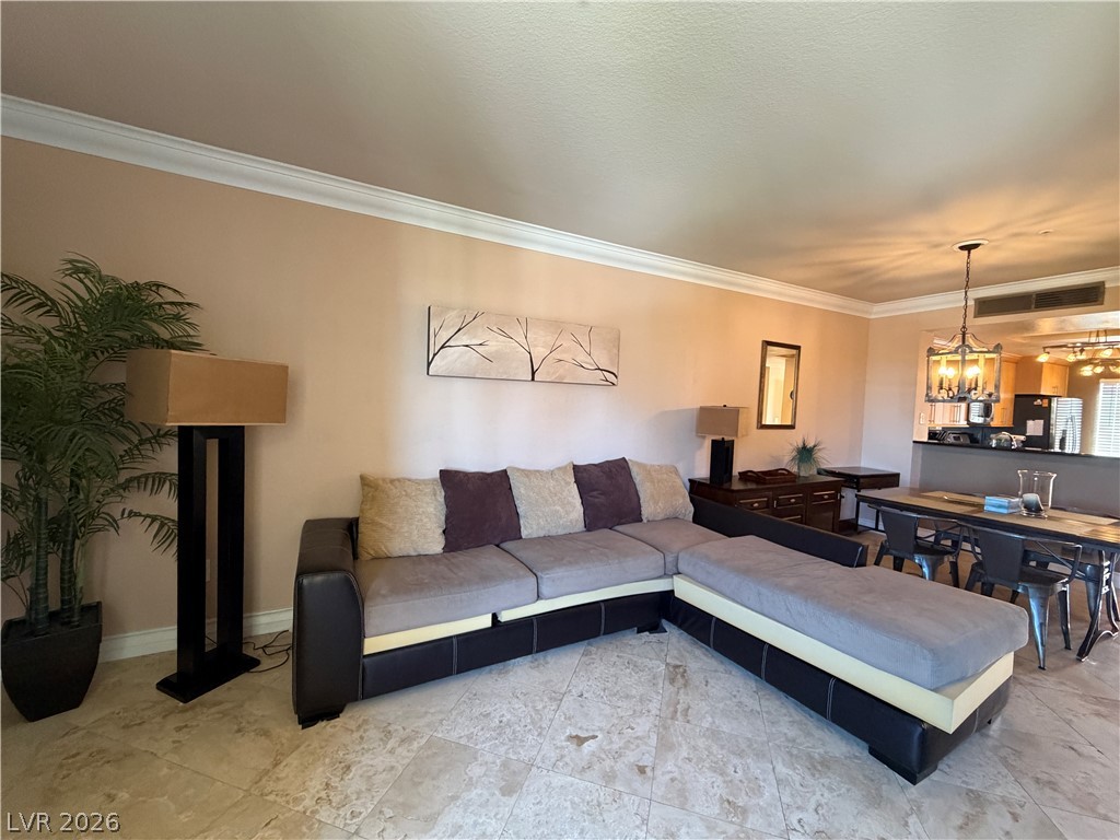 210 East Flamingo Road, Unit 426 Las Vegas, NV 89169 - Photo 6 of 17 Elegant crown molding complements the polished tile flooring, creating a refined living and dining space.