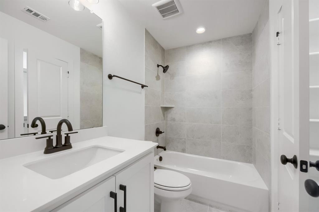 733 Red Cedar Road Haslet, TX 76052 - Photo 25 of 28 Bathroom featuring a white vanity with an integrated sink, dark bronze fixtures, light gray subway tile shower surround with a built-in niche, and recessed lighting